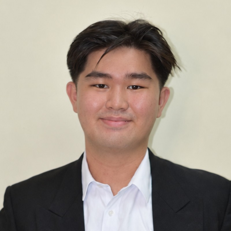 Carl Añonuevo smiling, wearing a black suit and white shirt